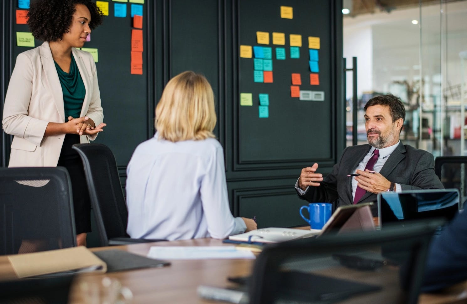 Man and two women in business attire in conference room discussing data wins