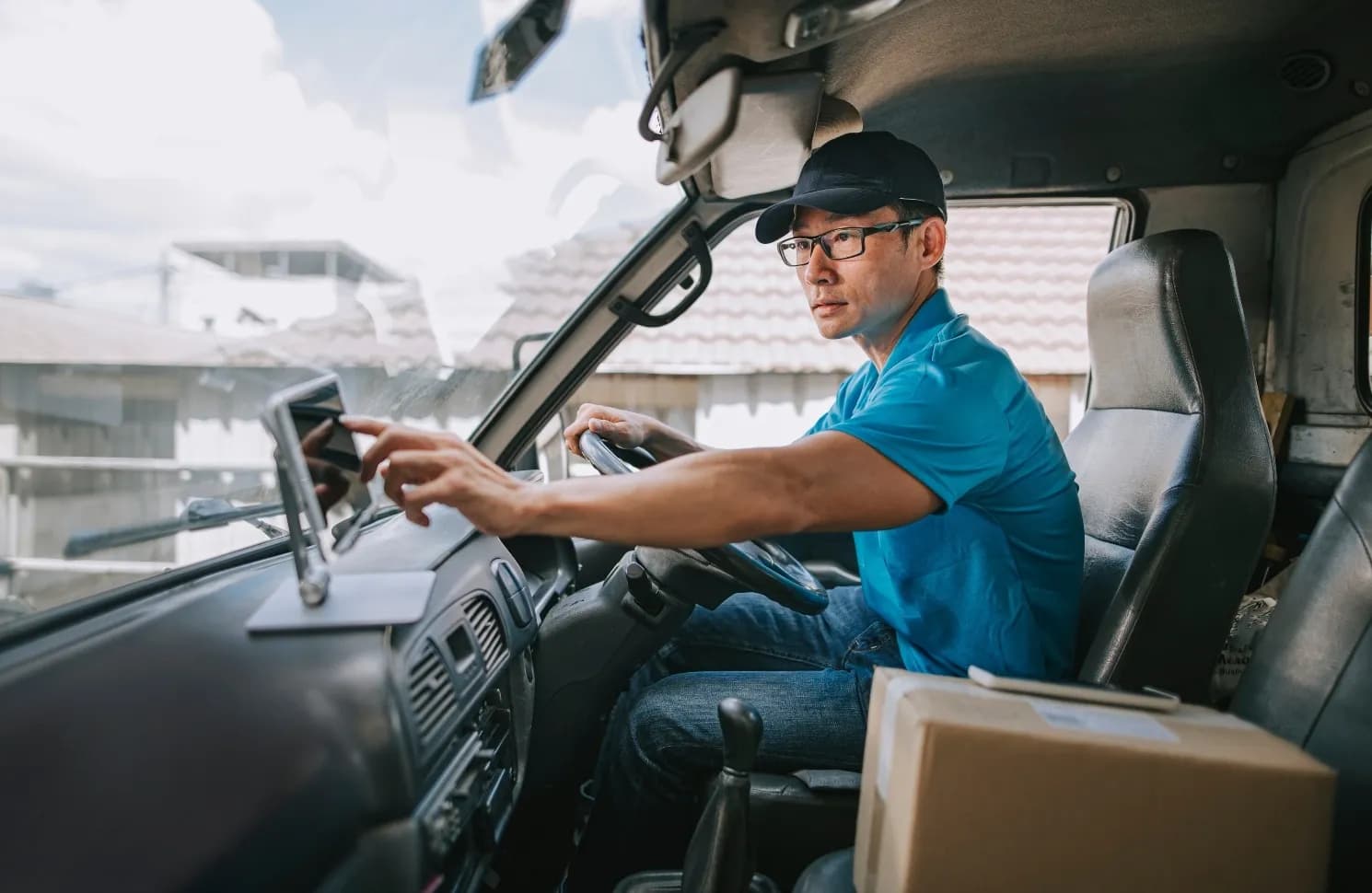 Delivery driver checking his route on his tablet before he delivers a box