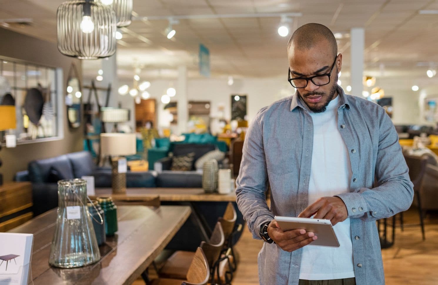 A man in a furniture store checks a tablet, representing a personalized shopping experience through AI