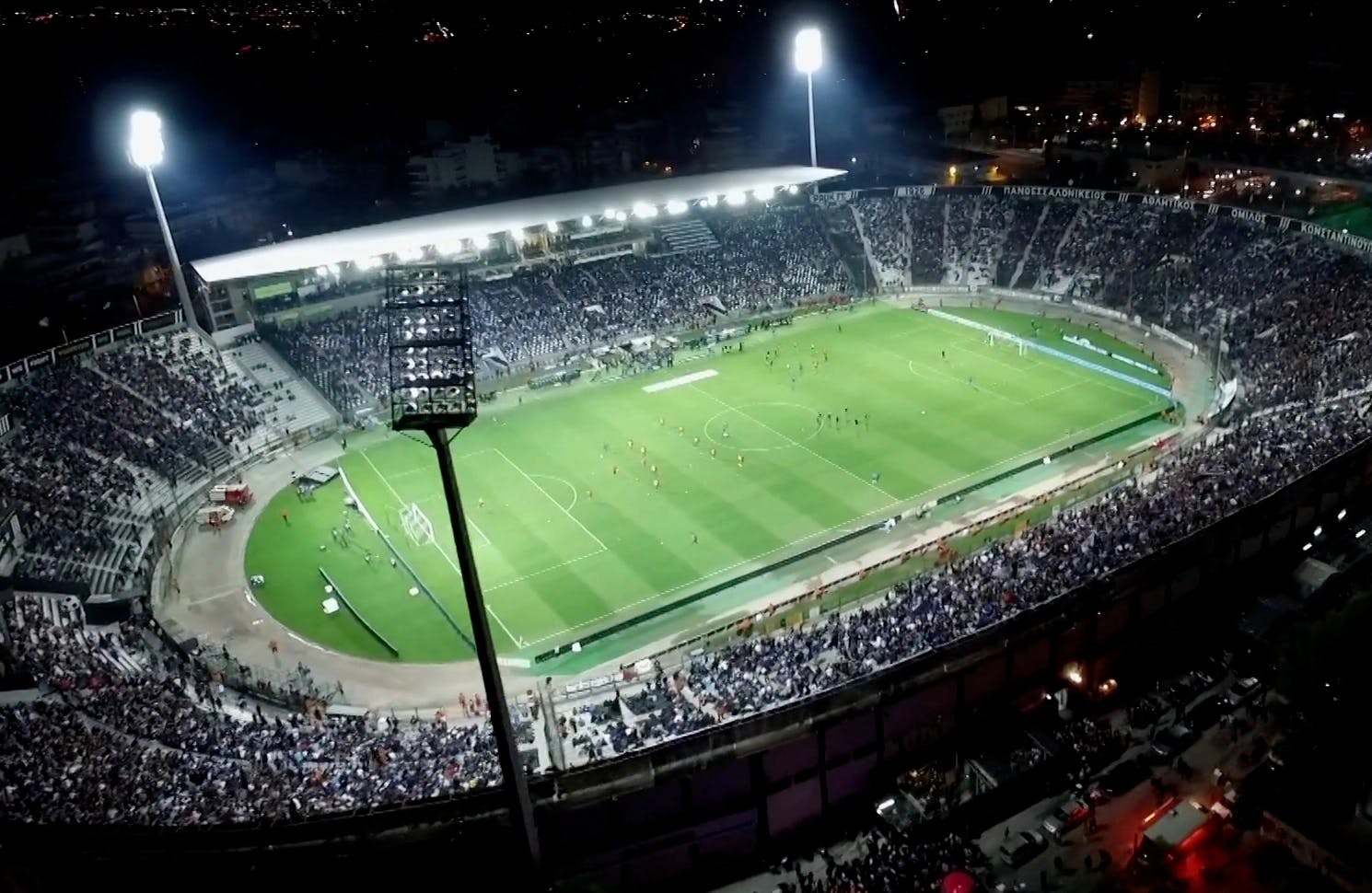 Birds eye view of a soccer field stadium filled with fans, soccer teams, and lights