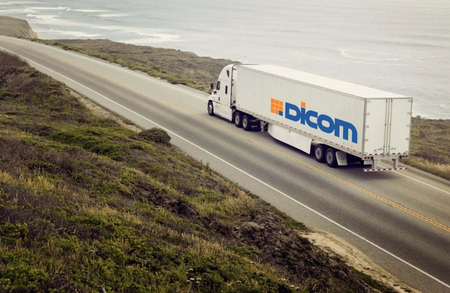 Coastal view of a Dicom Logistics semi driving on an ocean view highway