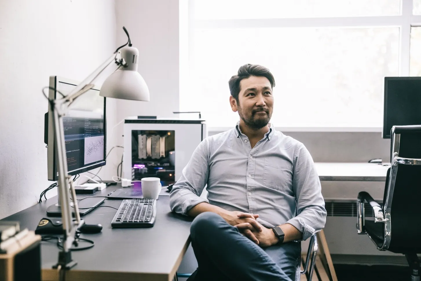 Male software developer sitting at his desk looking at someone with a smile